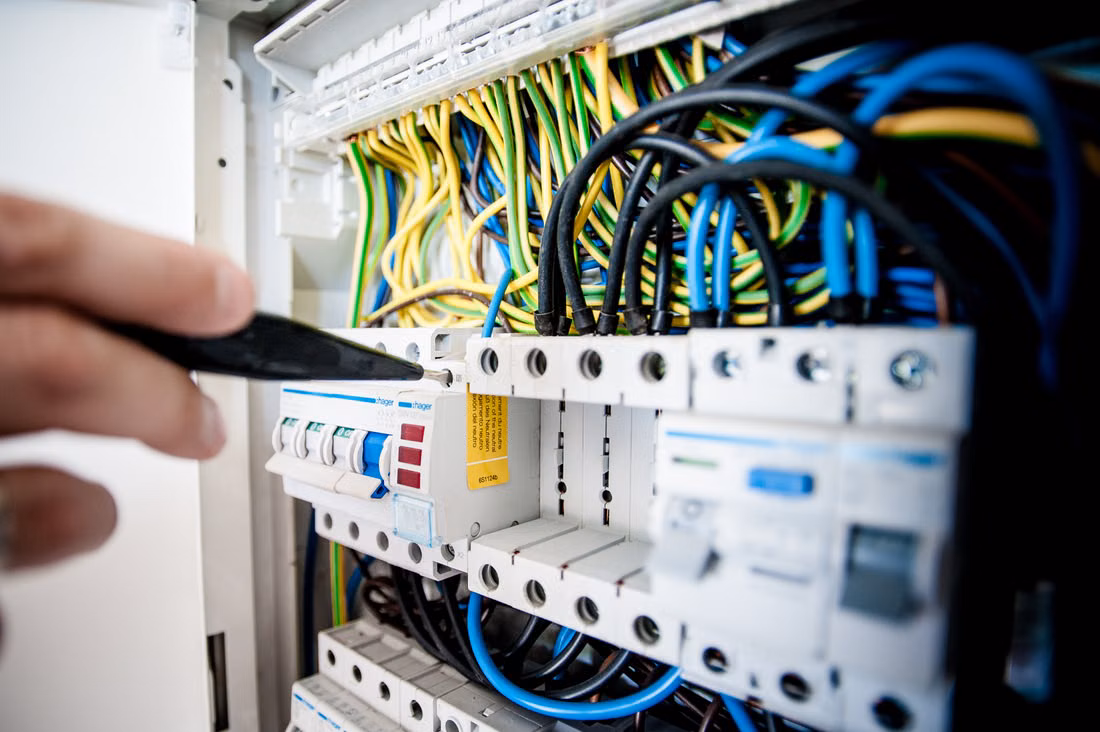 Electrical wiring technician working on an open circuit breaker board
